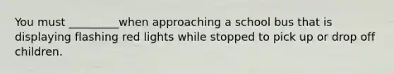 You must _________when approaching a school bus that is displaying flashing red lights while stopped to pick up or drop off children.