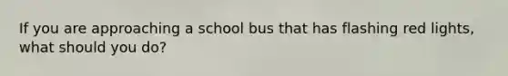 If you are approaching a school bus that has flashing red lights, what should you do?