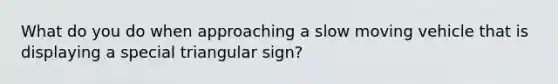 What do you do when approaching a slow moving vehicle that is displaying a special triangular sign?