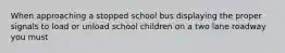 When approaching a stopped school bus displaying the proper signals to load or unload school children on a two lane roadway you must