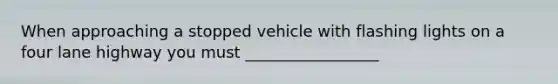 When approaching a stopped vehicle with flashing lights on a four lane highway you must _________________