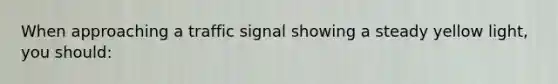 When approaching a traffic signal showing a steady yellow light, you should: