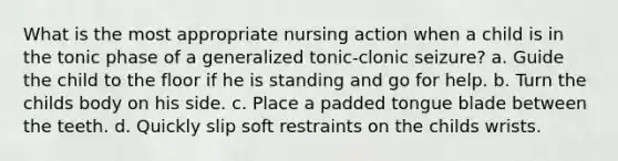 What is the most appropriate nursing action when a child is in the tonic phase of a generalized tonic-clonic seizure? a. Guide the child to the floor if he is standing and go for help. b. Turn the childs body on his side. c. Place a padded tongue blade between the teeth. d. Quickly slip soft restraints on the childs wrists.