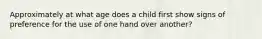 Approximately at what age does a child first show signs of preference for the use of one hand over another?