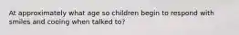 At approximately what age so children begin to respond with smiles and cooing when talked to?