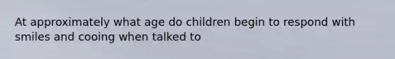 At approximately what age do children begin to respond with smiles and cooing when talked to