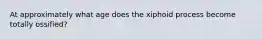 At approximately what age does the xiphoid process become totally ossified?