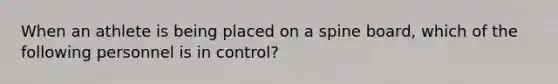 When an athlete is being placed on a spine board, which of the following personnel is in control?