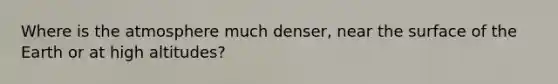 Where is the atmosphere much denser, near the surface of the Earth or at high altitudes?