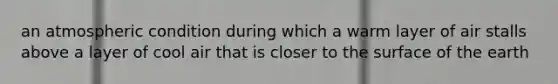 an atmospheric condition during which a warm layer of air stalls above a layer of cool air that is closer to the surface of the earth