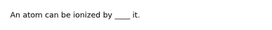 An atom can be ionized by ____ it.