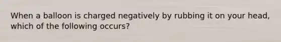 When a balloon is charged negatively by rubbing it on your head, which of the following occurs?