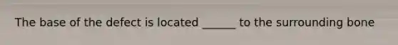 The base of the defect is located ______ to the surrounding bone