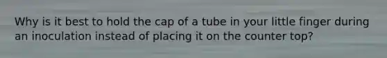 Why is it best to hold the cap of a tube in your little finger during an inoculation instead of placing it on the counter top?