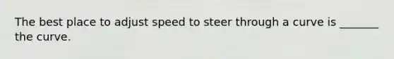 The best place to adjust speed to steer through a curve is _______ the curve.