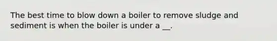 The best time to blow down a boiler to remove sludge and sediment is when the boiler is under a __.