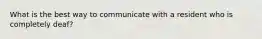 What is the best way to communicate with a resident who is completely deaf?