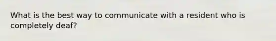 What is the best way to communicate with a resident who is completely deaf?