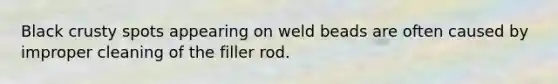 Black crusty spots appearing on weld beads are often caused by improper cleaning of the filler rod.