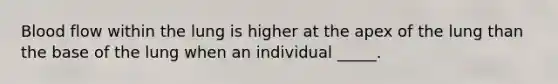 Blood flow within the lung is higher at the apex of the lung than the base of the lung when an individual _____.