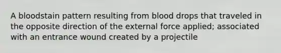 A bloodstain pattern resulting from blood drops that traveled in the opposite direction of the external force applied; associated with an entrance wound created by a projectile