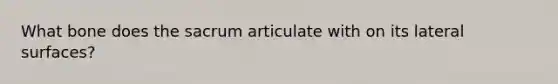 What bone does the sacrum articulate with on its lateral surfaces?