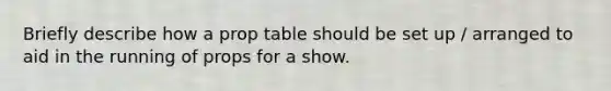 Briefly describe how a prop table should be set up / arranged to aid in the running of props for a show.