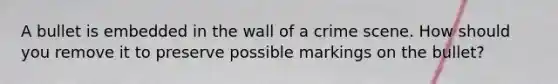 A bullet is embedded in the wall of a crime scene. How should you remove it to preserve possible markings on the bullet?