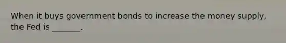 When it buys government bonds to increase the money supply, the Fed is _______.