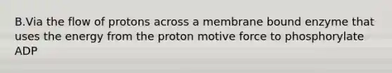 B.Via the flow of protons across a membrane bound enzyme that uses the energy from the proton motive force to phosphorylate ADP