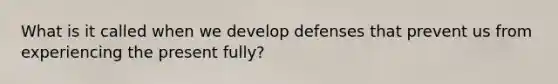 What is it called when we develop defenses that prevent us from experiencing the present fully?