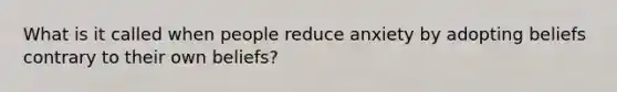 What is it called when people reduce anxiety by adopting beliefs contrary to their own beliefs?