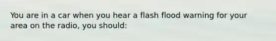 You are in a car when you hear a flash flood warning for your area on the radio, you should: