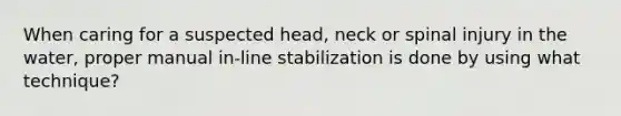 When caring for a suspected head, neck or spinal injury in the water, proper manual in-line stabilization is done by using what technique?