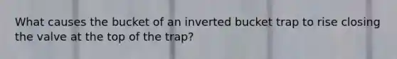 What causes the bucket of an inverted bucket trap to rise closing the valve at the top of the trap?