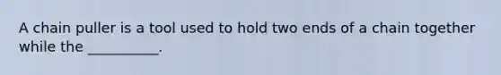 A chain puller is a tool used to hold two ends of a chain together while the __________.
