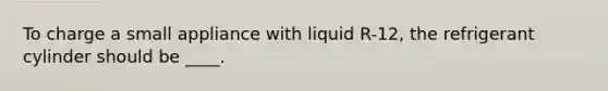 To charge a small appliance with liquid R-12, the refrigerant cylinder should be ____.