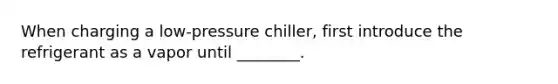 When charging a low-pressure chiller, first introduce the refrigerant as a vapor until ________.