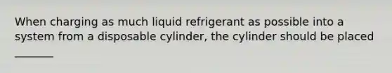 When charging as much liquid refrigerant as possible into a system from a disposable cylinder, the cylinder should be placed _______