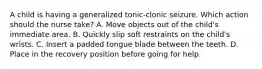 A child is having a generalized tonic-clonic seizure. Which action should the nurse take? A. Move objects out of the child's immediate area. B. Quickly slip soft restraints on the child's wrists. C. Insert a padded tongue blade between the teeth. D. Place in the recovery position before going for help.