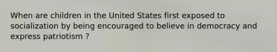 When are children in the United States first exposed to socialization by being encouraged to believe in democracy and express patriotism ?