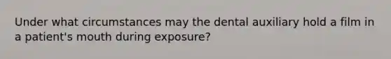 Under what circumstances may the dental auxiliary hold a film in a patient's mouth during exposure?