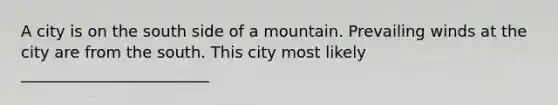 A city is on the south side of a mountain. Prevailing winds at the city are from the south. This city most likely ________________________