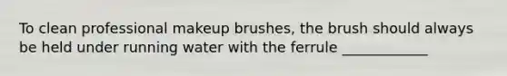 To clean professional makeup brushes, the brush should always be held under running water with the ferrule ____________