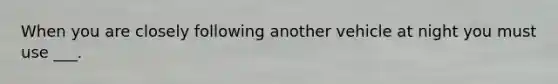 When you are closely following another vehicle at night you must use ___.