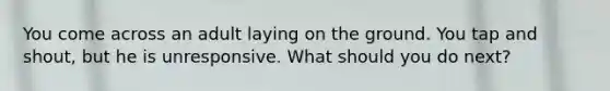 You come across an adult laying on the ground. You tap and shout, but he is unresponsive. What should you do next?