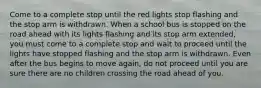 Come to a complete stop until the red lights stop flashing and the stop arm is withdrawn. When a school bus is stopped on the road ahead with its lights flashing and its stop arm extended, you must come to a complete stop and wait to proceed until the lights have stopped flashing and the stop arm is withdrawn. Even after the bus begins to move again, do not proceed until you are sure there are no children crossing the road ahead of you.