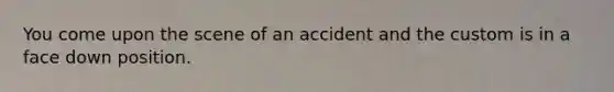 You come upon the scene of an accident and the custom is in a face down position.