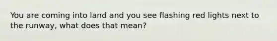 You are coming into land and you see flashing red lights next to the runway, what does that mean?