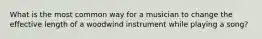 What is the most common way for a musician to change the effective length of a woodwind instrument while playing a song?